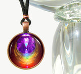 handmade round necklace with reiki-inspired art by Primal Painter featuring the seven chakras in a vertical line inside angel angel wings with a heart above and sealed under a glass dome