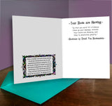 Open greeting card with text and decorative elements on a wooden surface.