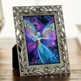 Framed mini art of a rainbow fairy with butterfly wings on a desk.