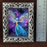 Framed artwork of a fairy with colorful wings on a brown background, next to a ruler for scale.