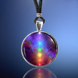 silver necklace against a blue background featuring chakra art with seven rainbow colors aligned in a straight line
