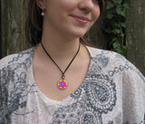 Star mandala art necklace in bright colors in a round silver setting. Shown on a model