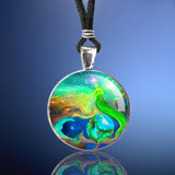 Handmade round necklace featuring Reiki attuned energy art by Primal Painter with a green angel, stars, earth, and moon print that's sealed under a glass dome