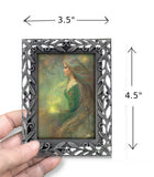 Framed mini goddess print of Elowen of the Woodland Realm by Primal Painter. Earth tones. Held in a hand with dimensions