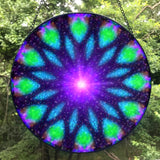 Back view of a Sacred geometry mandala glass suncatcher in blue, purple, and green with a purple starburst in the center and 12 sections. Artwork called Embrace Light by Primal Painter