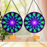 Front and back views of a Sacred geometry mandala glass suncatcher in blue, purple, and green with a purple starburst in the center and 12 sections. Artwork called Embrace Light by Primal Painter