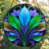 Textured glass suncatcher of a blue, green, and purple botanical leaf design. 