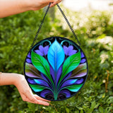 Textured glass suncatcher of a blue, green, and purple botanical leaf design. 