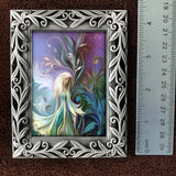Decorative frame with a fantasy-themed painting of a fairy surrounded by colorful foliage, next to a ruler for scale.