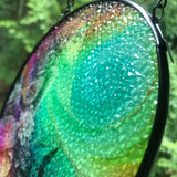 Side view showing textured glass of a Colorful round suncatcher featuring Flower Child by Primal Painter. Rainbow colors and flowers. 