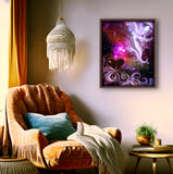 Abstract art print called The Guardian by Primal Painter featuring a stylized, multicolored depiction of a guardian angel with a heart symbol, moons, starts, and a goddess face in the bottom right. Framed hanging over a cozy chair