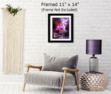 Abstract art print called The Guardian by Primal Painter featuring a stylized, multicolored depiction of a guardian angel with a heart symbol, moons, starts, and a goddess face in the bottom right. Framed hanging over a chair, 11x14