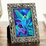 Decorative pewter frame with a colorful blue fairy design by Primal Painter on a wooden surface