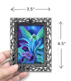 Framed artwork of a fairy with floral elements, held by a hand, with dimensions indicated.