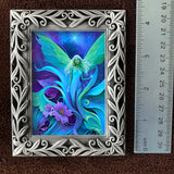 Framed artwork of a fairy with colorful wings and a flower, next to a ruler for scale.