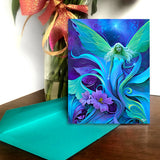 Greeting card featuring artwork by Primal Painter of an ethereal fairy amidst swirling art nouveau flowers and foliage in greens, purples, and blue. 