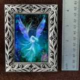 Framed artwork of a fairy with blue wings on a dark background, next to a ruler for scale.
