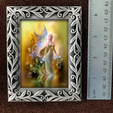 Framed artwork of a fairy with decorative frame and ruler for scale on a brown background