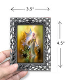 Framed artwork of a fairy held by a hand with dimensions indicated.