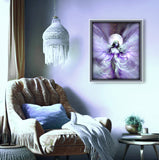 Framed artwork of a fairy on a wall above a cozy chair with a lamp and small table.