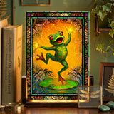 Small acrylic table lamp featuring a dancing frog artwork  in oranges, greens, and reds with a stained glass-effect border. Art by Primal Painter