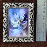 Decorative frame with a fairy painting and a ruler for scale on a brown background