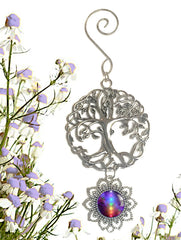 A pewter Tree of Life ornament with a hanging pendant featuring a rainbow chakra artwork, set against a background of purple flowers. Art by Primal Painter