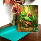 Greeting card featuring a colorful illustration of a frog lounging on a turtle with a cocktail, illustrated and created by Primal Painter.