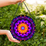 Textured glass mandala suncatcher featuring violet flame mandala artwork by Primal Painter in vivid purple, reds and orange. 