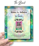 The back of a greeting card with colorful design and text held by a hand, featuring a QR code and website URL.