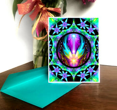 A colorful mandala-themed art card with a central angelic figure, surrounded by a vibrant pattern of stars and geometric shapes, on a green background. The card is blank on the inside for a personal message and includes a brightly colored envelope. Art by Primal Painter