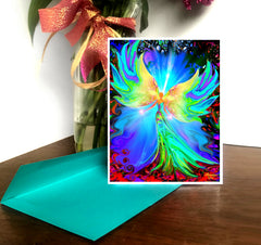 A greeting card featuring a colorful abstract angel artwork, placed on a desk with a green envelope and a decorative ribbon in the background. Art by Primal Painter
