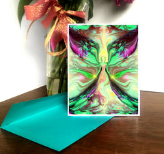 A greeting card featuring a colorful abstract design with pastel green, yellow, and pink swirls, and a central angel figure, set against a white background. The card is blank on the inside and comes with a brightly colored envelope. Art by Primal Painter