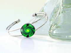 Green swirling artwork set under glass on a silver wire cuff bracelet by Primal Painter