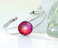 Bright magenta abstract art featuring chakra colors in a circle, displayed under glass on a silver wire bracelet cuff by Primal Painter