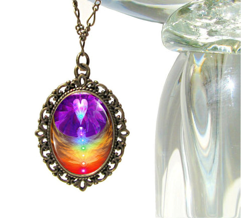 oval victorian style necklace featuring angel wings artwork with seven chakras in a row under a heart and sealed under a glass dome