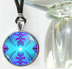 A throat chakra and third eye energy necklace with a geometric pattern in blue, purple, and teal colors, featuring a silver or antique copper finished brass setting and a black suede faux leather cord.