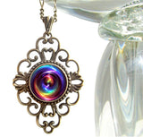 bronze lacy filligree necklace featuring a rainbow chakra swirl print sealed under a glass dome