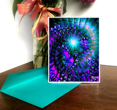 A greeting card with a vibrant, abstract Fibonacci spiral design in purple and blue hues, displayed on a desk with a green envelope and a decorative ribbon in the background. Art by Primal Painter