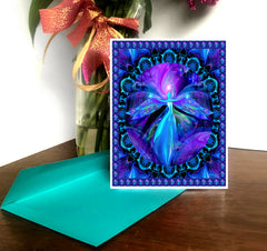 A greeting card with a colorful mandala design and a fairy angel in the center, set against a purple background. The card comes with a brightly colored envelope. Art by Primal Painter